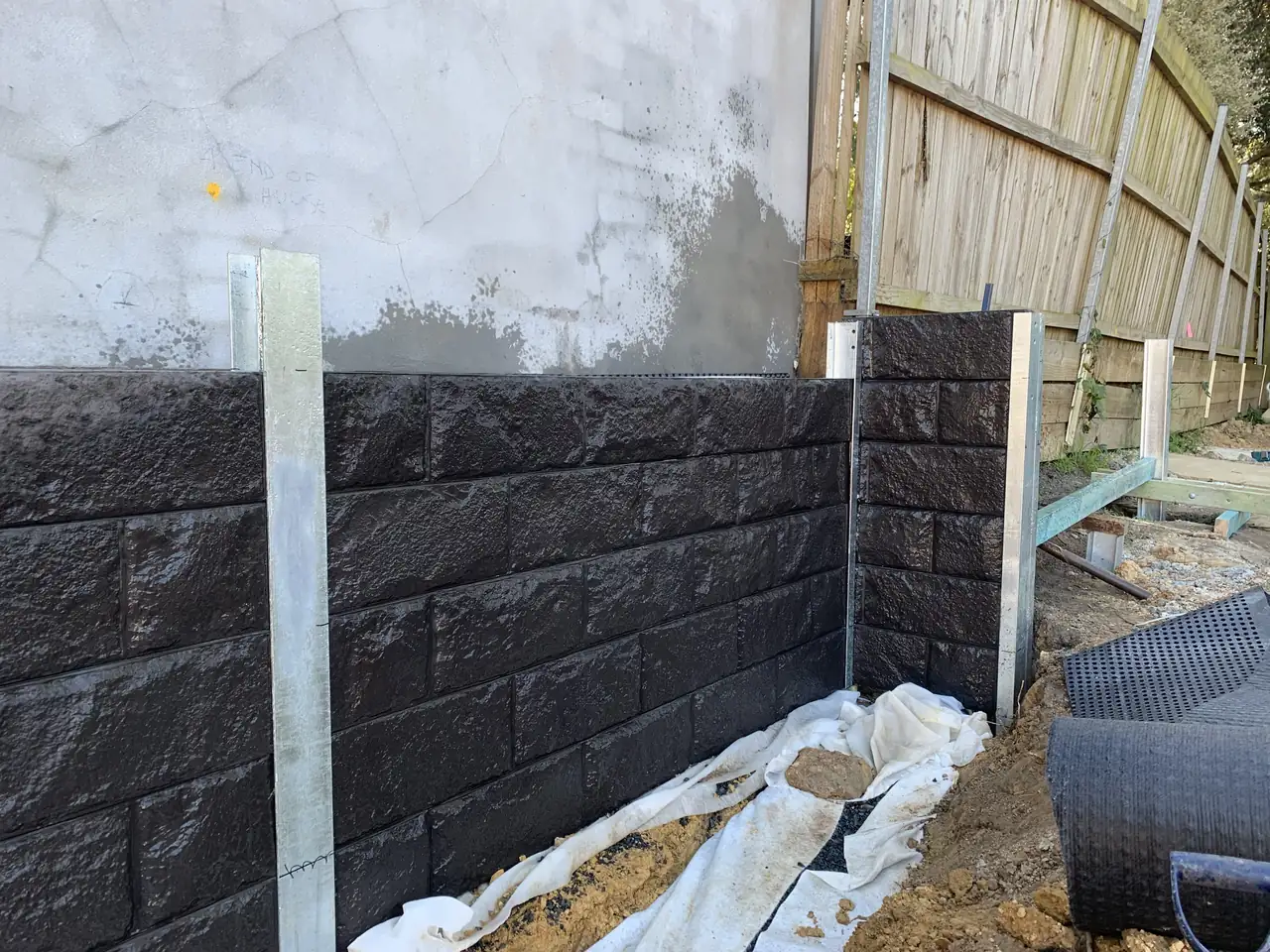 Close-up of charcoal rock-face concrete sleepers and galvanised steel post