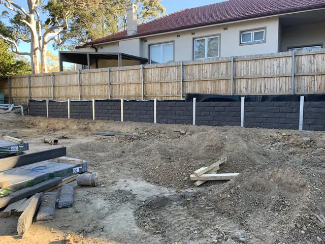 Charcoal concrete sleeper retaining wall with galvanised posts in a Sydney backyard
