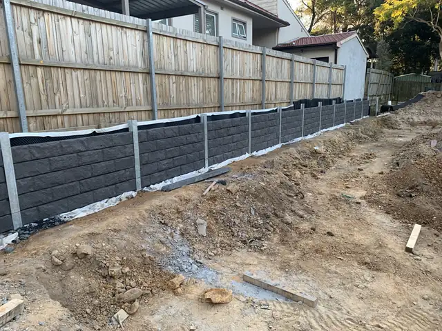 Concrete sleepers being installed between galvanised steel posts