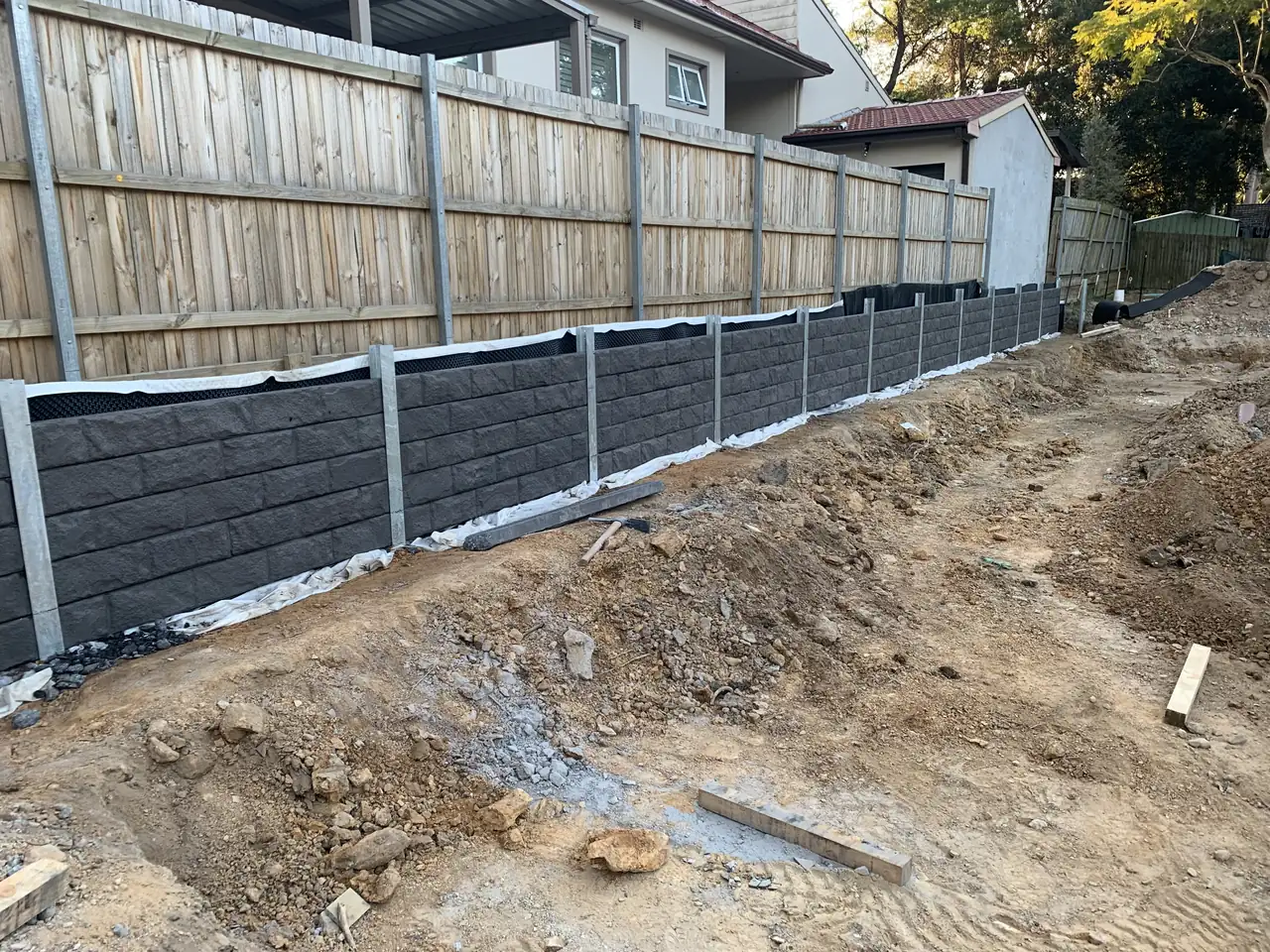 Concrete sleepers being installed between galvanised steel posts