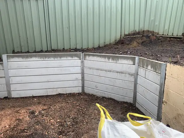 L-shaped white concrete sleeper retaining wall creating a level garden area