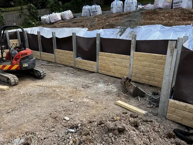 Sandstone-look concrete sleepers being installed with an excavator